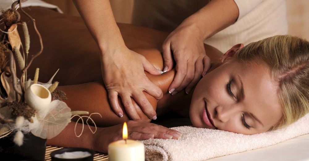 En kvinde får en afslappende massage i et atmosfærisk rum med stearinlys og pynt.