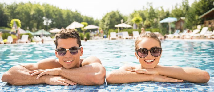 Smilende par i stor swimmingpool
