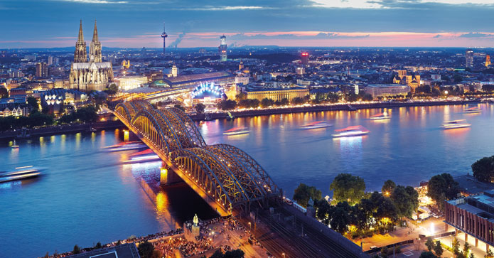 Aftenbelysning fremhæver broerne over Rhine og Kölns ikonisk katedral i baggrunden.