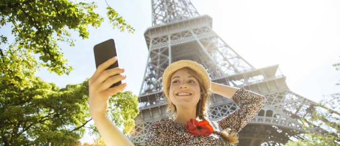 Ung kvinde tager selfie foran Eiffeltårnet i Paris